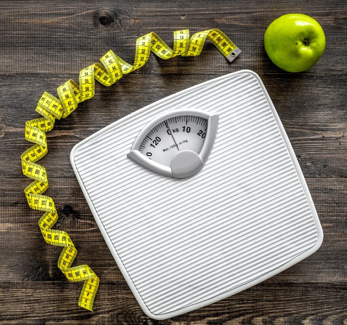 Lose weight concept. Bathroom scale, measuring tape, apples on wooden background top view