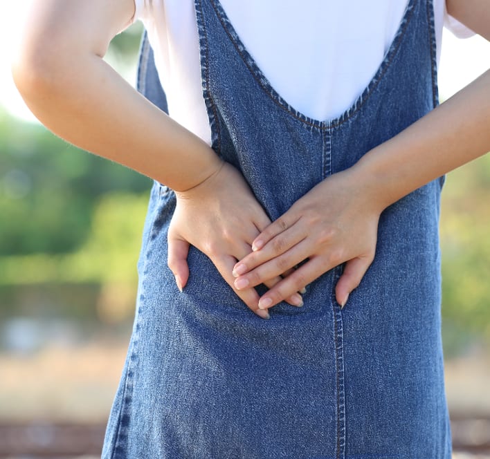 young woman feeling lower back pain on nature background