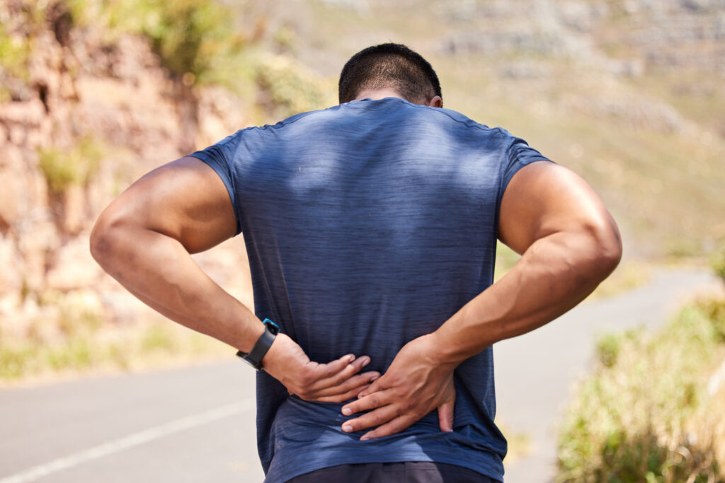 Man holding lower back outdoors with back pain not improving with rest